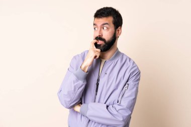 Sakallı, ceketli, soyutlanmış arka planda sinirli ve korkmuş beyaz bir adam.