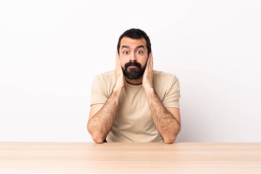 Masada sakallı beyaz bir adam hayal kırıklığına uğramış ve kulaklarını kapatmış..