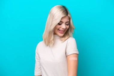 Yara bandı takan genç Rus kadın mutlu bir ifadeyle mavi arka planda izole edilmiş.