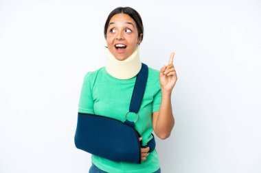 Boynunda boyunluk ve askısı olan genç İspanyol kadın beyaz arka planda izole edilmiş bir şekilde parmak kaldırmayı düşünüyor.