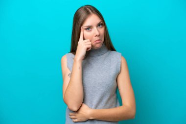 Genç Litvanyalı kadın mavi arka planda izole edilmiş bir fikir düşünüyor.