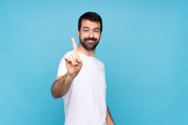 Mavi arka planda sakallı genç bir adam parmağını kaldırıyor ve gösteriyor.