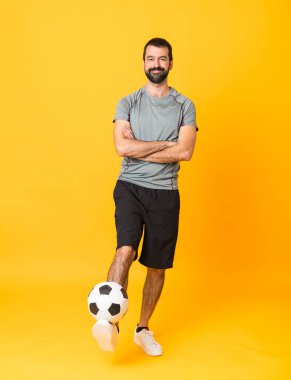 İzole edilmiş sarı arka planda bir futbolcunun tam boy çekimi.