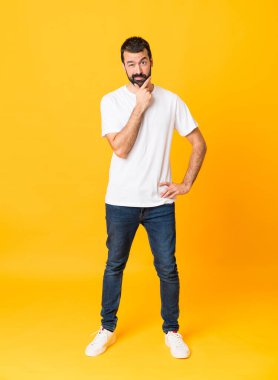 İzole edilmiş sarı arka planda sakallı bir adamın tam boy fotoğrafı.
