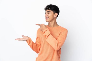 İzole edilmiş beyaz arka plan üzerinde genç bir adam bir reklam eklemek için avucunun içinde hayali bir alan tutuyor.