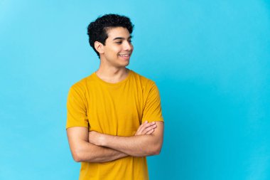 Genç Venezuelalı adam mavi arka planda izole edilmiş mutlu ve gülümsüyor