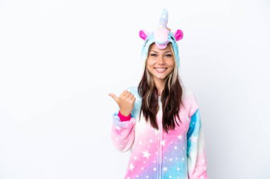 Beyaz arka planda izole edilmiş tek boynuzlu at pijaması giyen genç Rus kadın bir ürünü sunmak için kenarı işaret ediyor.