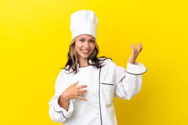 Genç Rus şef kız sarı arka planda izole edilmiş gitar hareketi yapıyor.