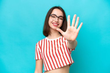 Mavi arka planda izole edilmiş genç Ukraynalı kadın parmaklarıyla beşi sayıyor