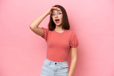 Pembe arka planda izole edilmiş genç Ukraynalı bir kadın. Önüne bakarken sürpriz jest yapıyor.