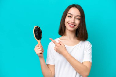 Mavi arka planda saç tarağı olan genç Ukraynalı bir kadın.
