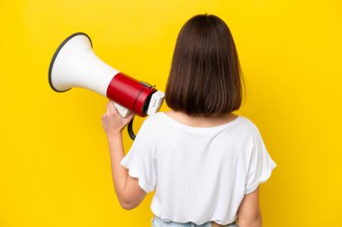 Sarı arka planda izole edilmiş genç Ukraynalı bir kadın elinde megafonla arka planda duruyor.