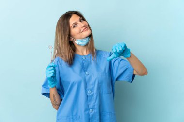 Slovak dişçi mavi arkaplanda kendini beğenmiş ve gururlu araçlar tutuyor