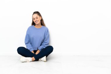 Genç bayan yerde oturmuş gülüyor.