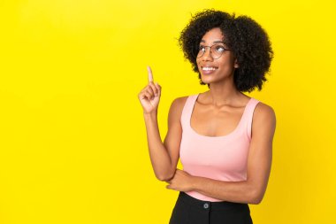Sarı arka planda izole edilmiş genç Afrikalı Amerikalı kadın harika bir fikre işaret ediyor.