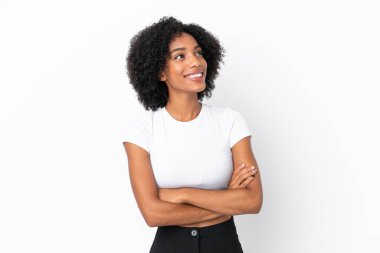 Beyaz arka planda izole edilmiş genç Afrikalı Amerikalı kadın gülümserken yukarı bakıyor.