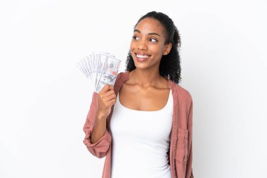 Genç Afrikalı Amerikalı bir kadın, beyaz arka planda izole edilmiş bir sürü para alıyor. Yan bakıp gülümsüyor.