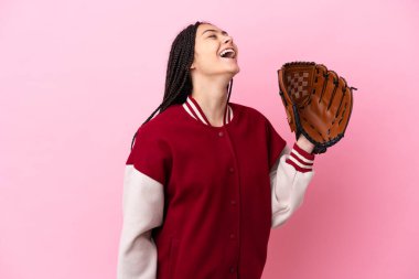 Beyzbol eldiveni olan genç oyuncu pembe arka planda izole edilmiş ve yan pozisyonda gülüyor.