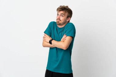 Beyaz arka planda izole edilmiş genç yakışıklı omuzlarını kaldırırken şüphe jestleri yapıyor.