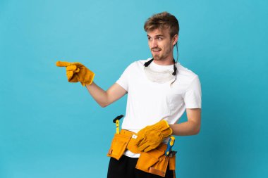 Genç elektrikçi, izole edilmiş duvarın üzerinden parmak göstererek bir ürün sunuyor.