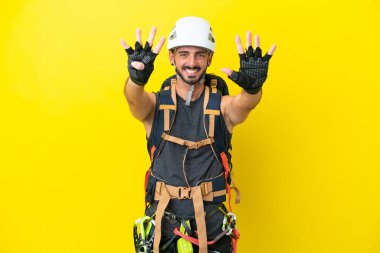 Sarı arka planda izole edilmiş beyaz dağcı dokuz parmağıyla sayıyor.