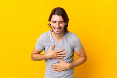 Sarı arka planda izole edilmiş genç yakışıklı adam çok gülümsüyor.