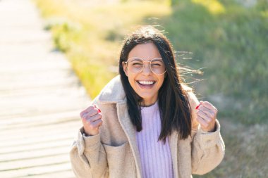 Açık havada genç bir kadın Gözlüklü ve zaferi kutlayan