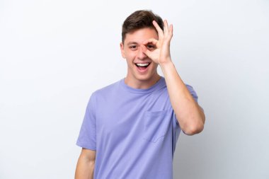 Beyaz arka planda izole edilmiş yakışıklı Brezilyalı adam parmaklarıyla işaret veriyor.