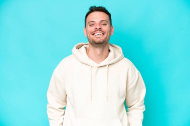 Genç beyaz yakışıklı adam mavi arka planda izole edilmiş gülüyor.