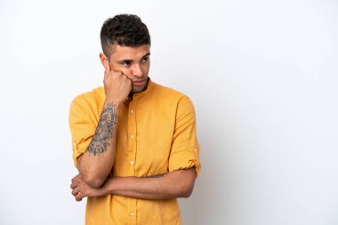 Beyaz arka planda, yorgun ve sıkılmış bir ifadeyle izole edilmiş beyaz Brezilyalı genç bir adam.