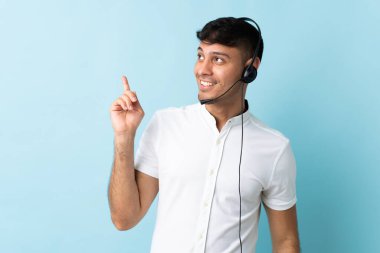 Kolombiyalı tele pazarlamacı, izole edilmiş arka planda kulaklıkla çalışıyor. Çözümü bulmak için parmağını kaldırıyor.