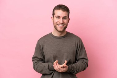 Pembe arka planda izole edilmiş genç beyaz adam gülüyor.