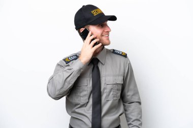 Beyaz arka planda izole edilmiş genç bir güvenlik görevlisi cep telefonuyla sohbet ediyor.