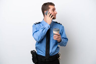 Beyaz arka planda izole edilmiş genç bir beyaz adam elinde kahve ve bir cep telefonu tutuyor.