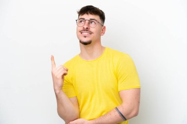 Beyaz arka planda izole edilmiş beyaz, yakışıklı genç bir adam harika bir fikre işaret ediyor.