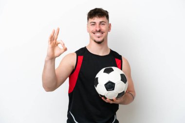 Beyaz arka planda futbol topuyla izole edilmiş beyaz tenli yakışıklı bir adam.