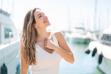 Genç, güzel bir kadın açık havada, mutlu bir ifadeyle.