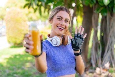 Dışarıda elinde portakal suyu tutan genç ve güzel bir bayan mutlu bir ifadeyle selamlıyor.