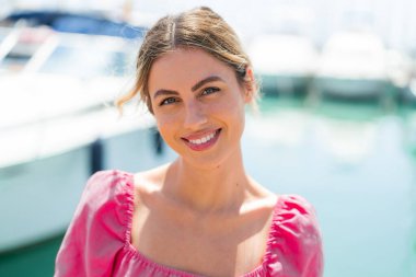 Açık havada genç sarışın bir kadın Neşeli bir ifadeyle