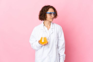 Pembe arka planda izole edilmiş genç İngiliz bilim kadını yan tarafa bakıyor.