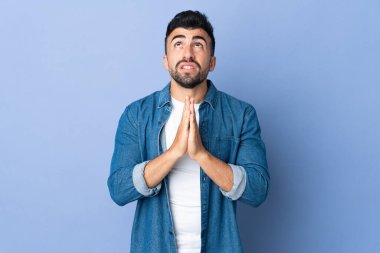 İzole edilmiş mavi geçmişi olan beyaz bir adam avuç içlerini bir arada tutar. İnsan bir şey ister.