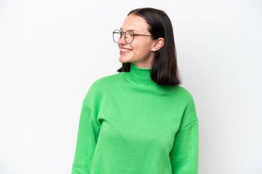 Beyaz arka planda izole edilmiş genç beyaz kadın yan bakıyor ve gülümsüyor.