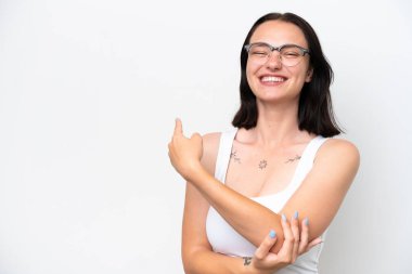 Beyaz arka planda gözlüklü ve işaret eden beyaz tenli genç bir kadın.