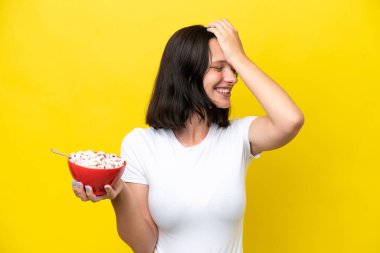 Sarı arka planda bir kase mısır gevreği tutan genç beyaz kadın bir şey fark etti ve çözüme niyetlendi.