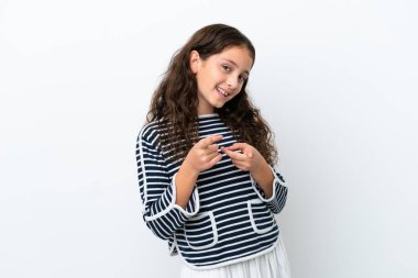 Beyaz arka planda izole edilmiş küçük beyaz kız şaşırmış ve ön tarafı işaret ediyor.