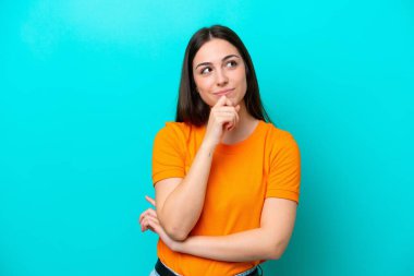 Genç beyaz kadın mavi arka planda izole edilmiş ve yukarı bakıyor.