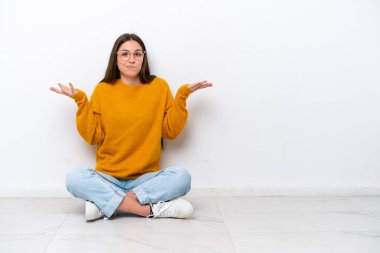 Beyaz arka planda izole bir şekilde yerde oturan genç kız ellerini kaldırırken şüpheleri vardı.