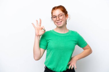 Young reddish woman isolated on white background showing ok sign with fingers