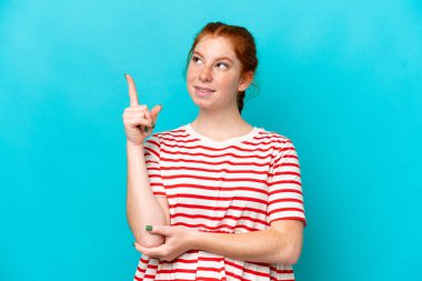 Mavi arka planda izole edilmiş genç bir kadın harika bir fikre işaret ediyor.