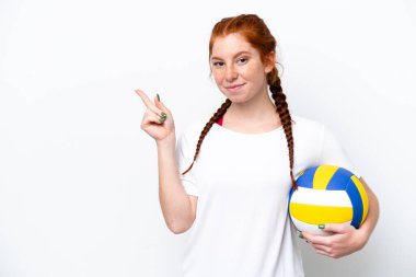 Beyaz arka planda yalıtılmış voleybol oynayan beyaz tenli, kızıl saçlı genç bir kadın.
